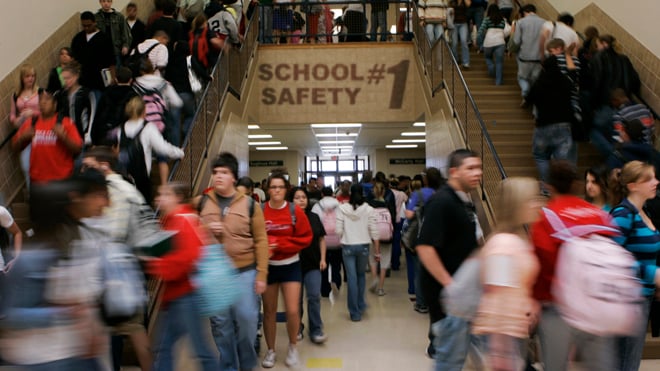 Students crowding a hallway as they head to class, with the sign "School Safety #1" on the wall above them.