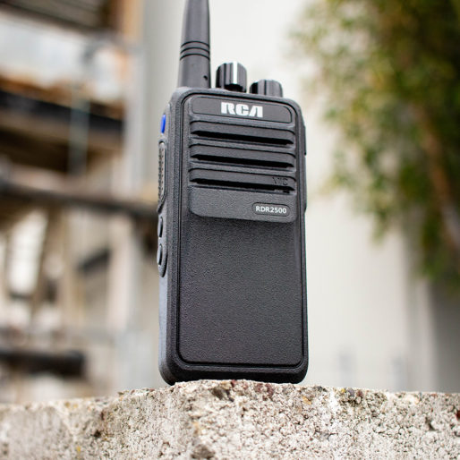 An RDR2500 industrial two-way radio sits upright on a concrete wall outdoors.